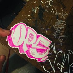 someone is holding up a sticker with pink graffiti on it