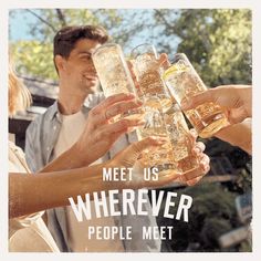 people are toasting with drinks in front of a poster that reads meet us wherever people meet