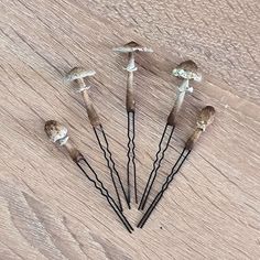 five small mushrooms sitting on top of a wooden table next to each other with wire