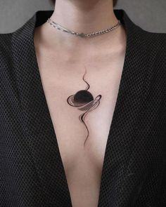 a woman's chest with a black and white tattoo on her left side breast