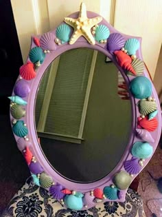 a mirror that is sitting on top of a chair in front of a door with seashells around it