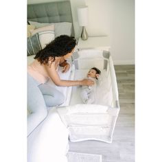 a woman is looking at a baby in a crib