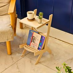 a small table with two books on it next to a chair and potted plant