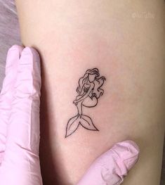 a little mermaid tattoo on the side of a woman's thigh, with her arm behind her back