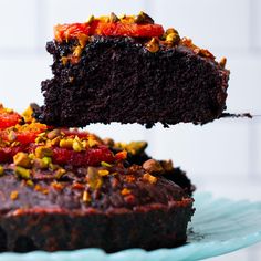 a piece of chocolate cake is being lifted from the plate by a fork with another slice on it