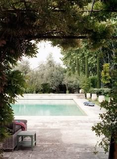 an outdoor swimming pool surrounded by greenery and stone pavers flooring is seen through the archways