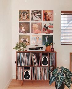 a record player sitting on top of a wooden shelf next to a wall filled with records