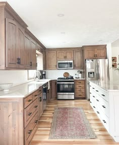 a kitchen with wooden cabinets and white counter tops, an area rug on the floor