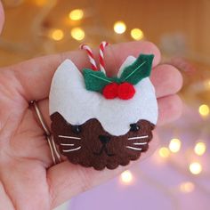 a hand holding a small felt ornament with a cat on it's head