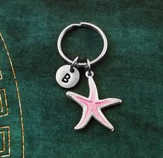 a starfish keychain with the letter b on it sitting on a green blanket