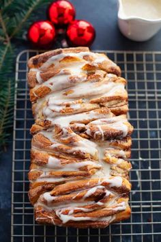 a loaf of cinnamon bread with icing on a cooling rack next to christmas decorations