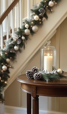 a christmas garland with pine cones and balls on the bannister next to a candle