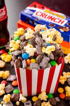 a cup full of popcorn and candy on top of a table next to other snacks