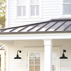 a white house with two black lamps on the front porch