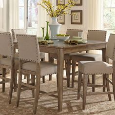 a dining room table and chairs in front of a window with flowers on the table