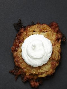 fried food with sour cream on top sitting on a black surface