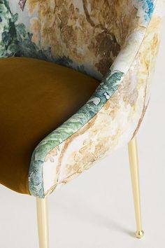 an upholstered chair with floral fabric and gold legs