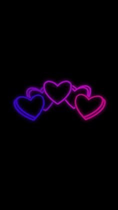 three heart shaped neon lights against a black background