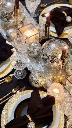 the table is set with black and gold place settings, silverware, and napkins