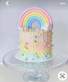 there is a cake that has been decorated with rainbows and clouds on top of it