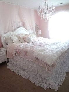 a white bed sitting in a bedroom next to a window with a chandelier