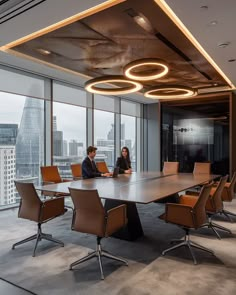 two people sitting at a conference table in an office with large windows overlooking the city