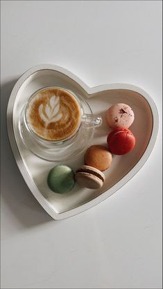 there is a heart shaped tray with different types of food on it and a cup of cappuccino in the middle