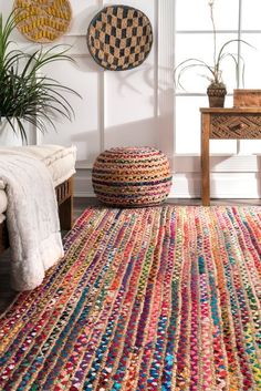 a multicolored rug in a living room with two plants on the wall and one floor