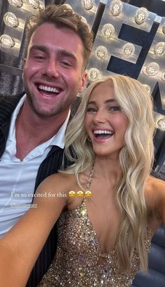 a man and woman posing for a photo in front of a sign that says i'm so excited for this