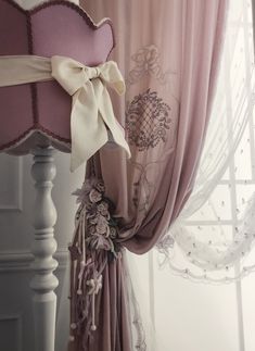 the curtains are hanging on the side of the bed, and there is a bow at the top