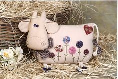 a stuffed cow sitting next to a basket with flowers on it's side and another animal in the background