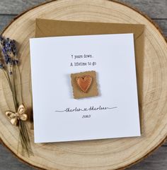 a card with a heart shaped cookie on it sitting on top of a wooden plate