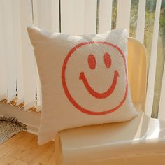 a white pillow with a red smiley face drawn on it sitting on top of a chair