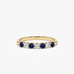 a yellow gold ring with three blue sapphire stones on the side and one white diamond in the middle