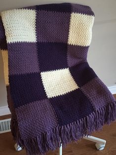 a purple and white blanket sitting on top of a chair