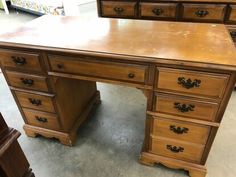 a wooden desk with drawers on top of it in a room filled with other furniture