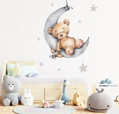 a teddy bear sitting on the moon wall sticker in a child's room