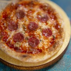 a pepperoni pizza sitting on top of a wooden plate