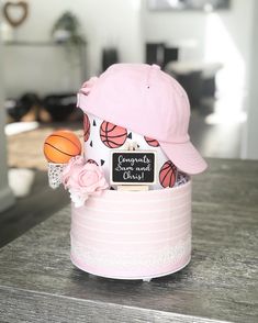 a pink hat with basketballs and flowers in it on top of a wooden table