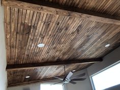 a ceiling fan mounted to the side of a wooden ceiling