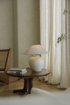 a white lamp sitting on top of a table next to a chair and window sill