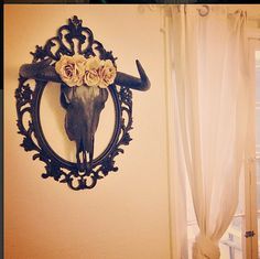 a cow skull mounted to the side of a wall with flowers on it's head