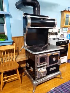 an old fashioned stove in the middle of a kitchen with wooden floors and blue walls