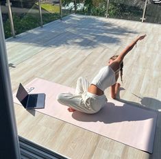 a woman is doing yoga outside on her laptop