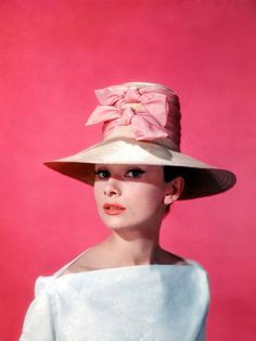 a woman wearing a white dress and hat with pink bow on it's brim