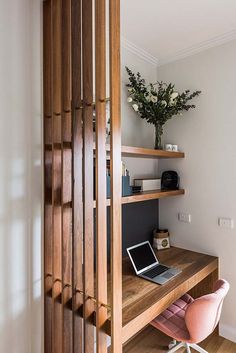 a laptop computer sitting on top of a wooden desk next to a book shelf filled with books