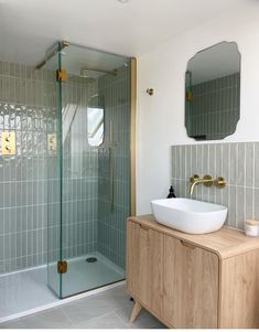 a bathroom with a sink, mirror and stand up shower stall in it's corner