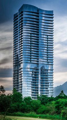 a very tall building sitting in the middle of a lush green field next to trees