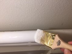 a person holding a paintbrush in their hand and painting the ceiling with white paint