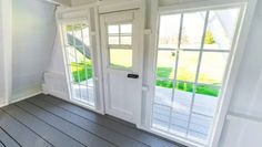 an empty room with white walls and wooden floors, two doors open to the outside